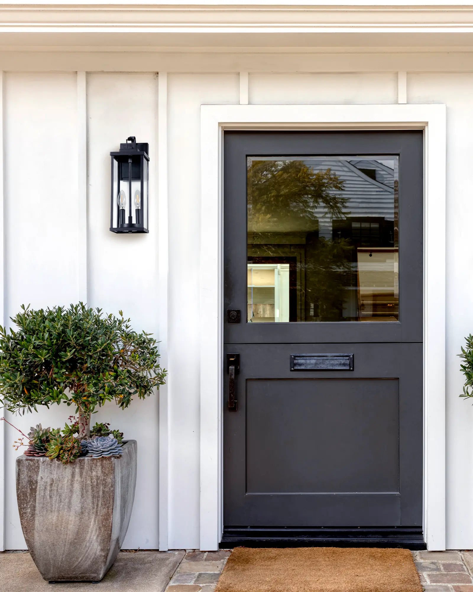 Dark gray front door with glass panel on a white house exterior.