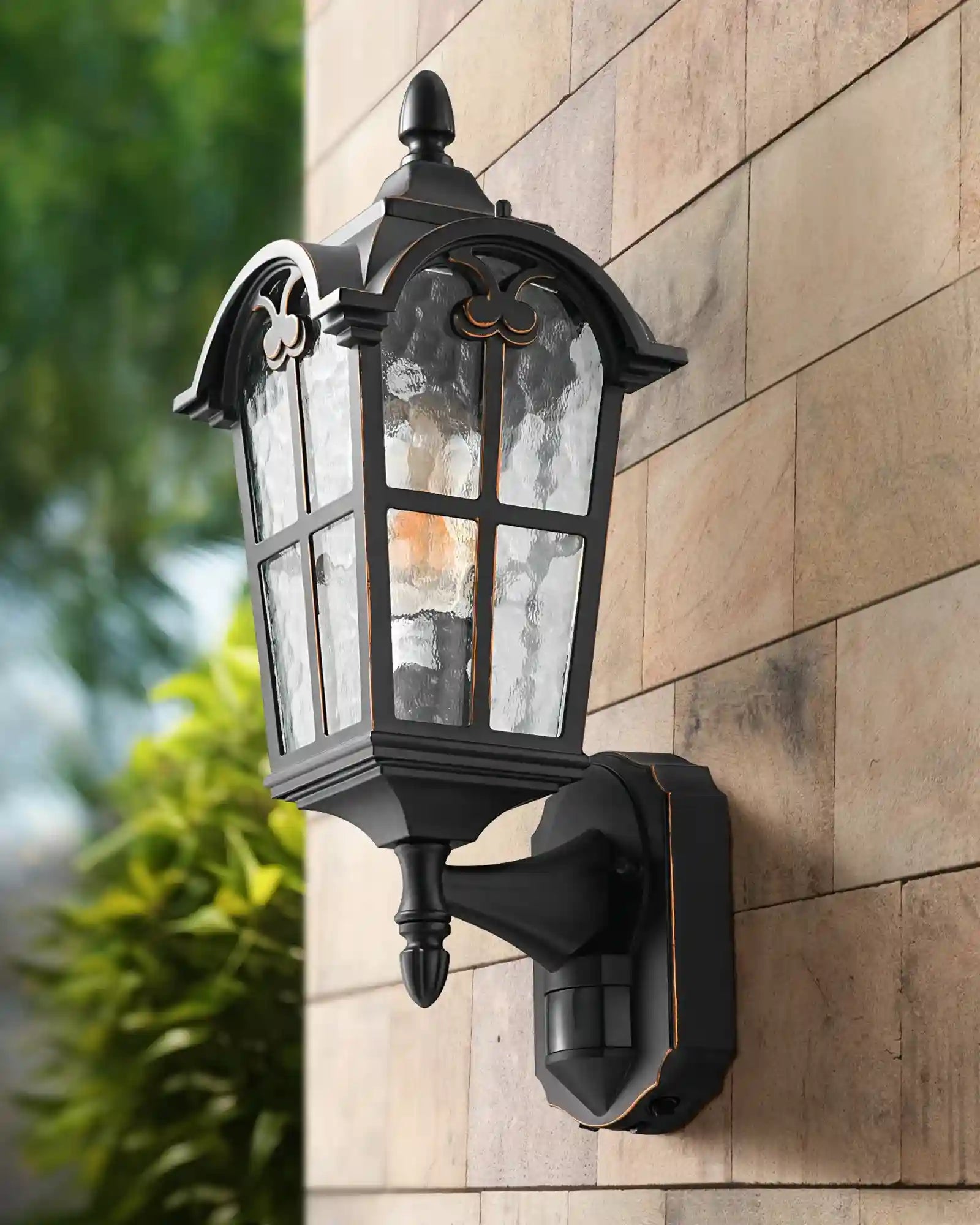 EDISHINE Outdoor Wall Light with Dusk to Dawn and Motion Sensor on a stone wall with greenery in the background