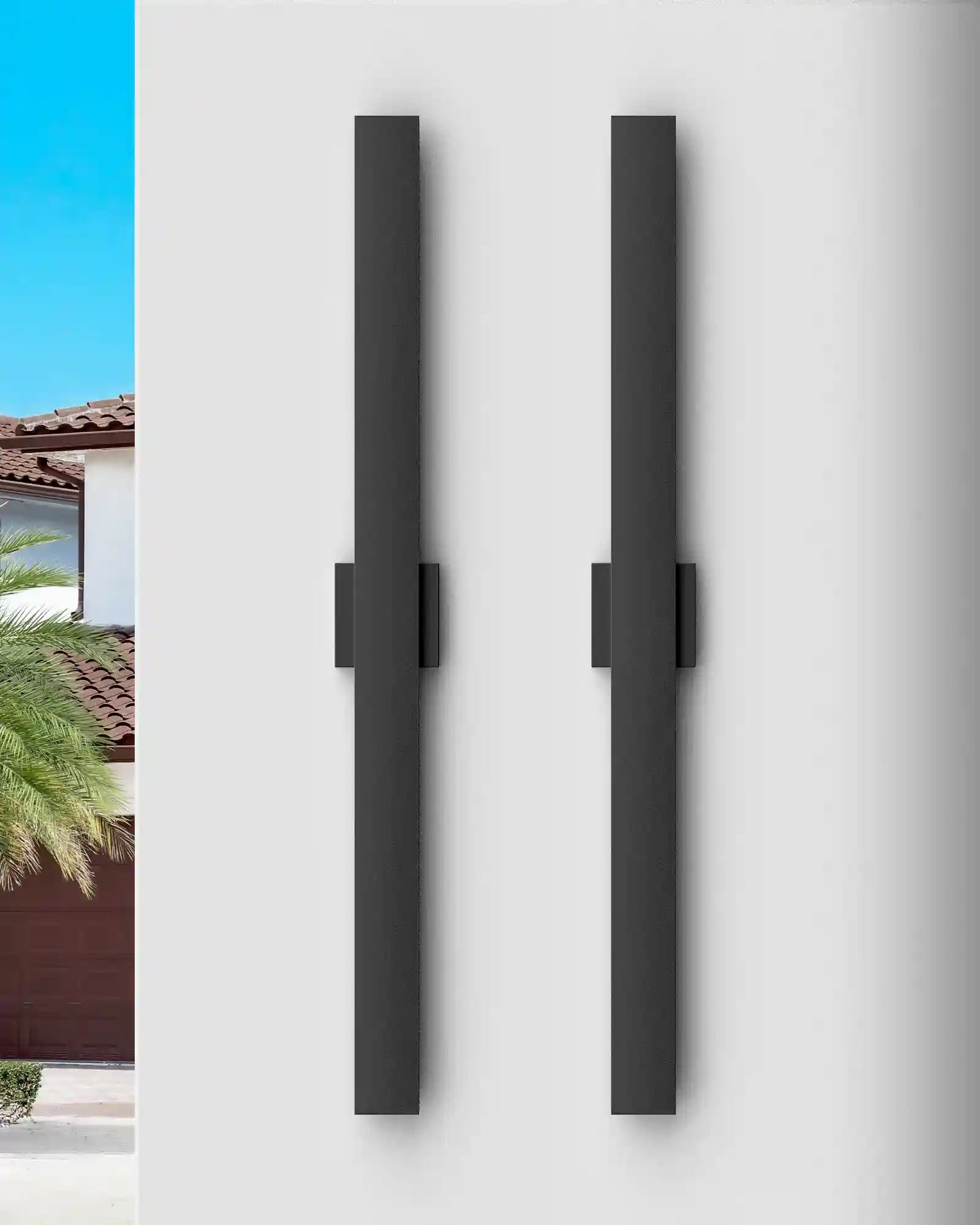 Two black rectangular EDISHINE 2 Pack 39.3" Modern Outdoor Wall Lights Dimmable on a white wall with a house and blue sky in the background.