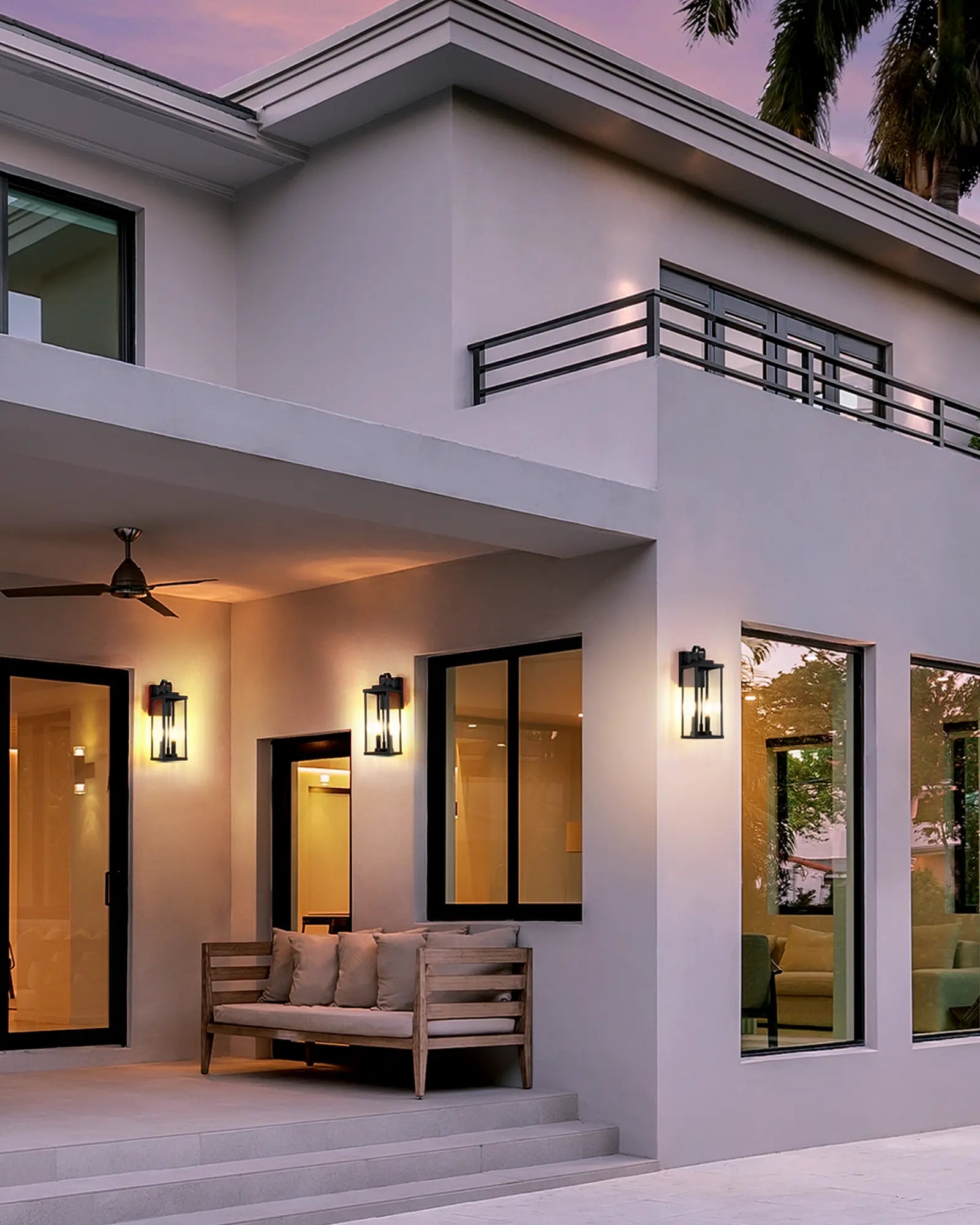 Modern house exterior with a couch, lamps, and large windows.