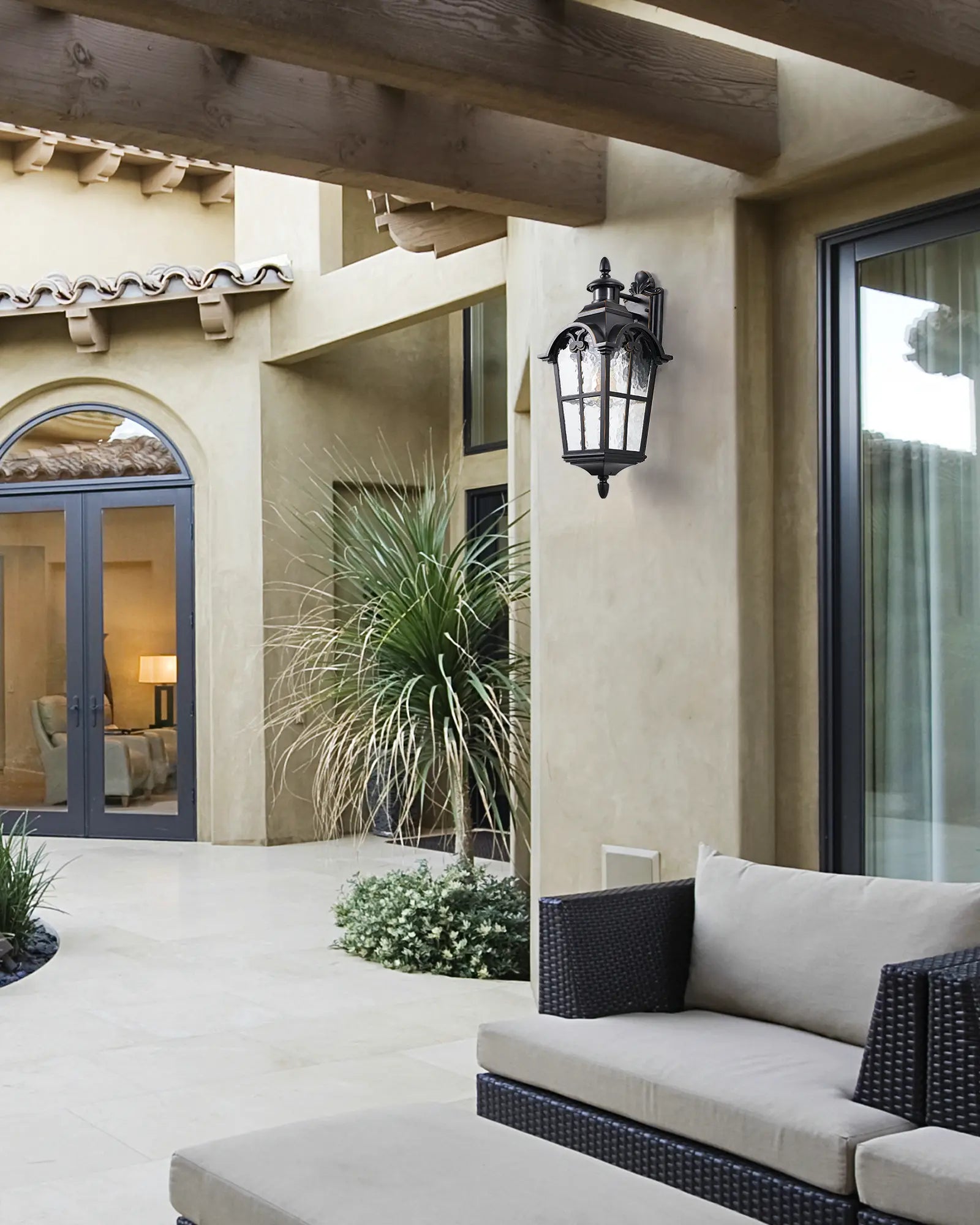 Outdoor patio area with a couch, lamp, and plants in a residential setting