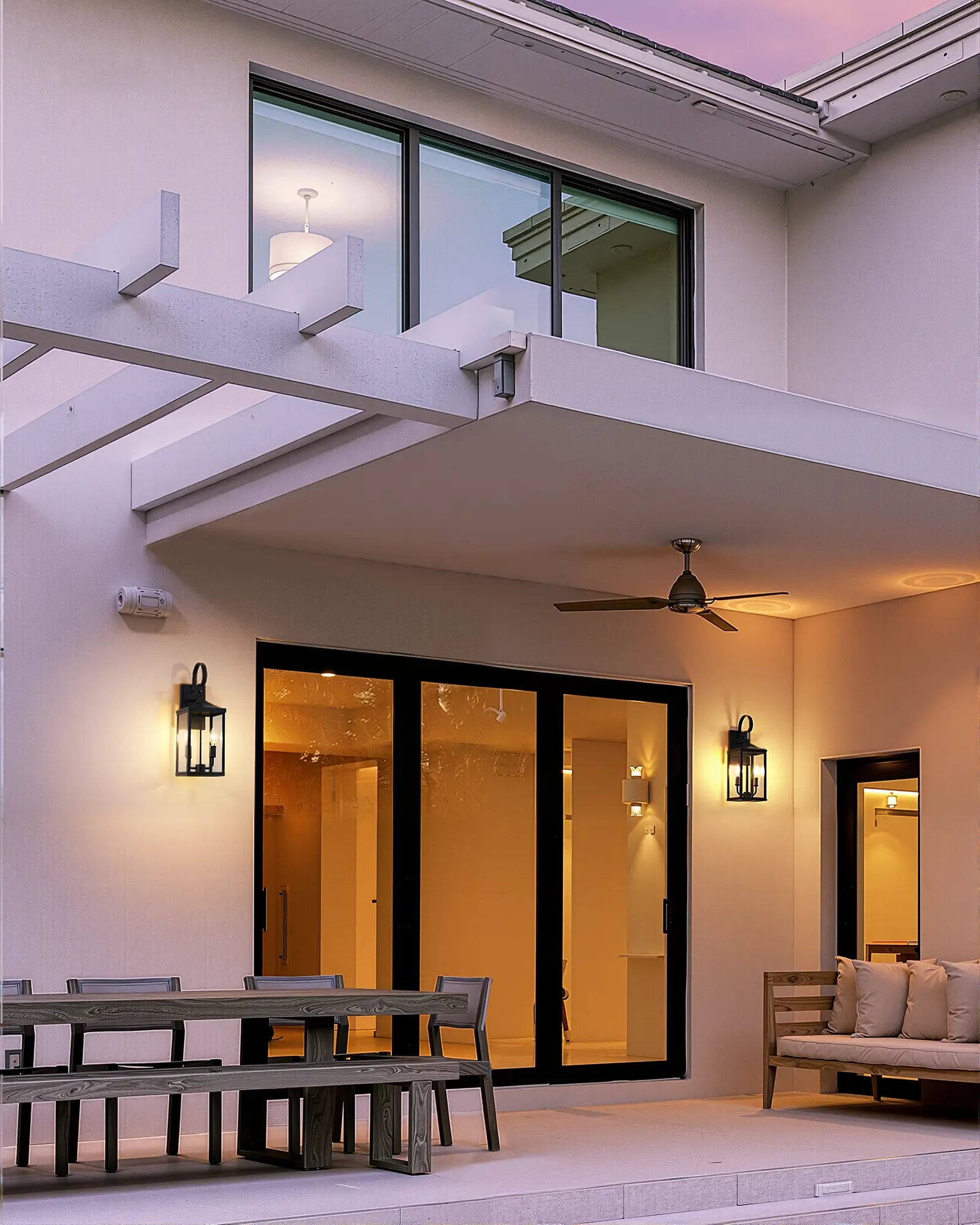 Modern outdoor patio area with seating and EDISHINE 19'' Dusk To Dawn Outdoor Wall Lantern on a house exterior.
