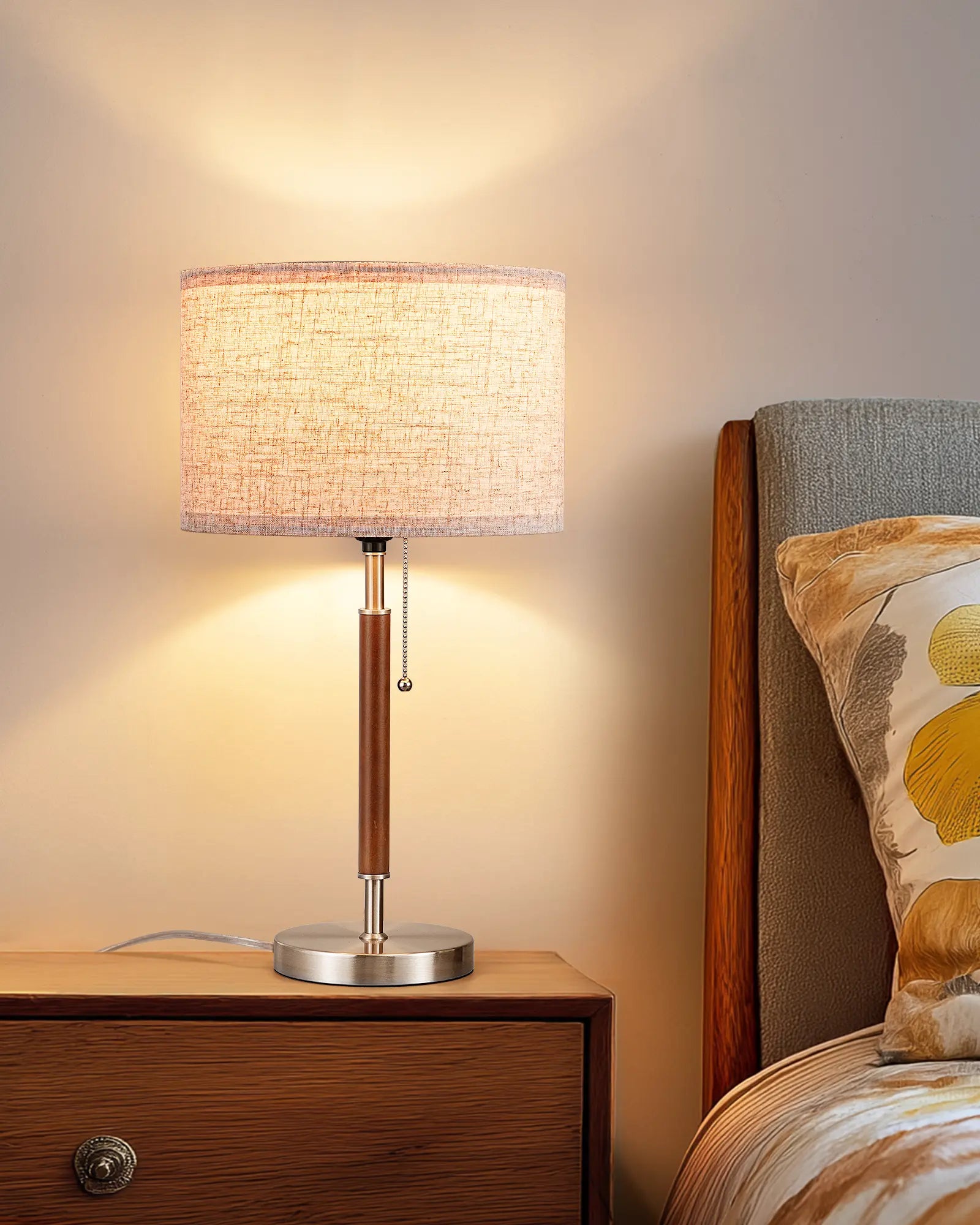 Table lamp with wooden and metal design on a desk next to an alarm clock.