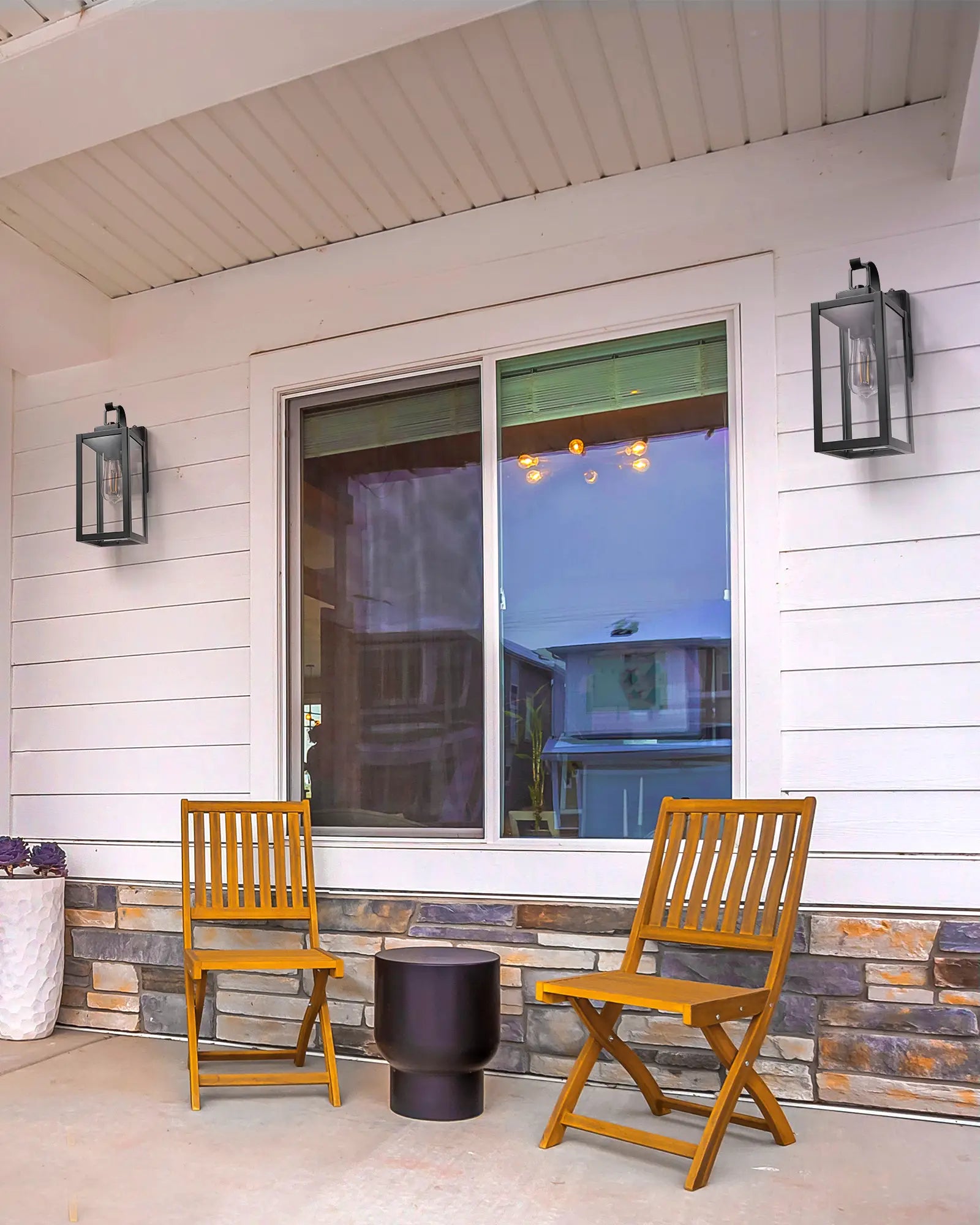 Two wooden chairs and a small table on a patio with a house and Dusk to Dawn Outdoor Wall Lantern