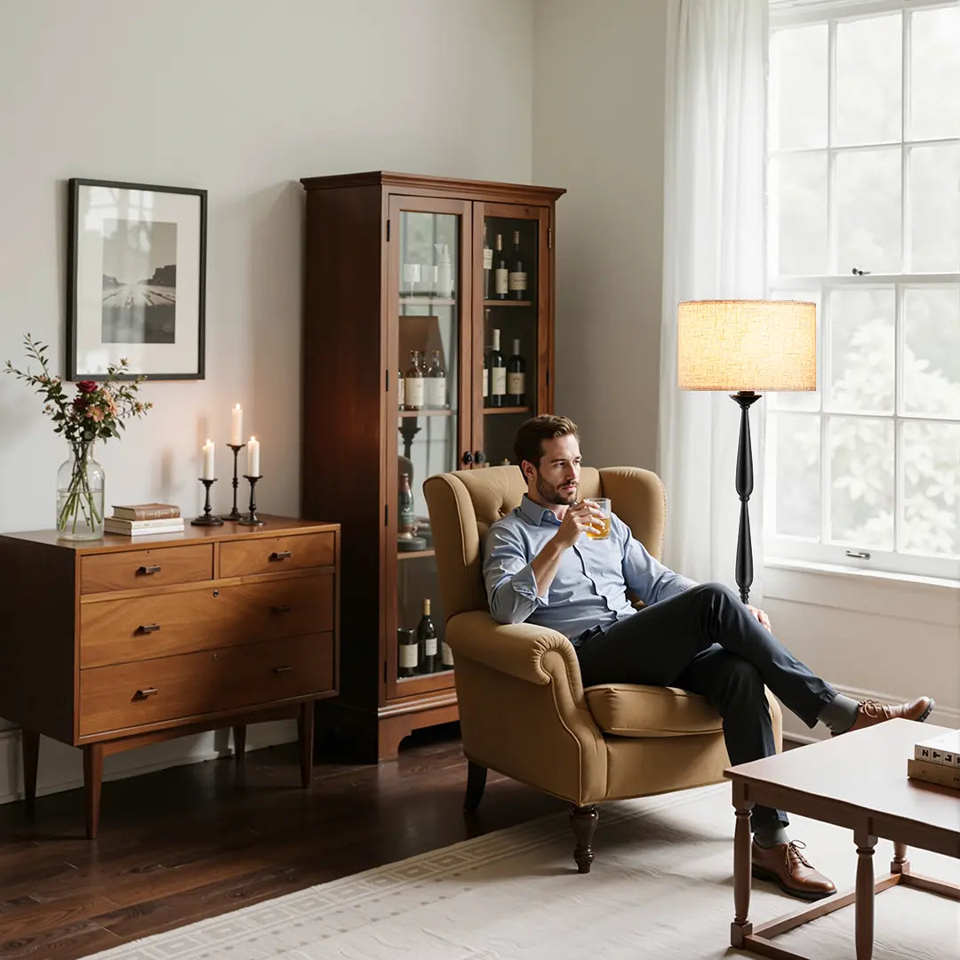Man sitting in a chair in a living room with wooden furniture and decor.