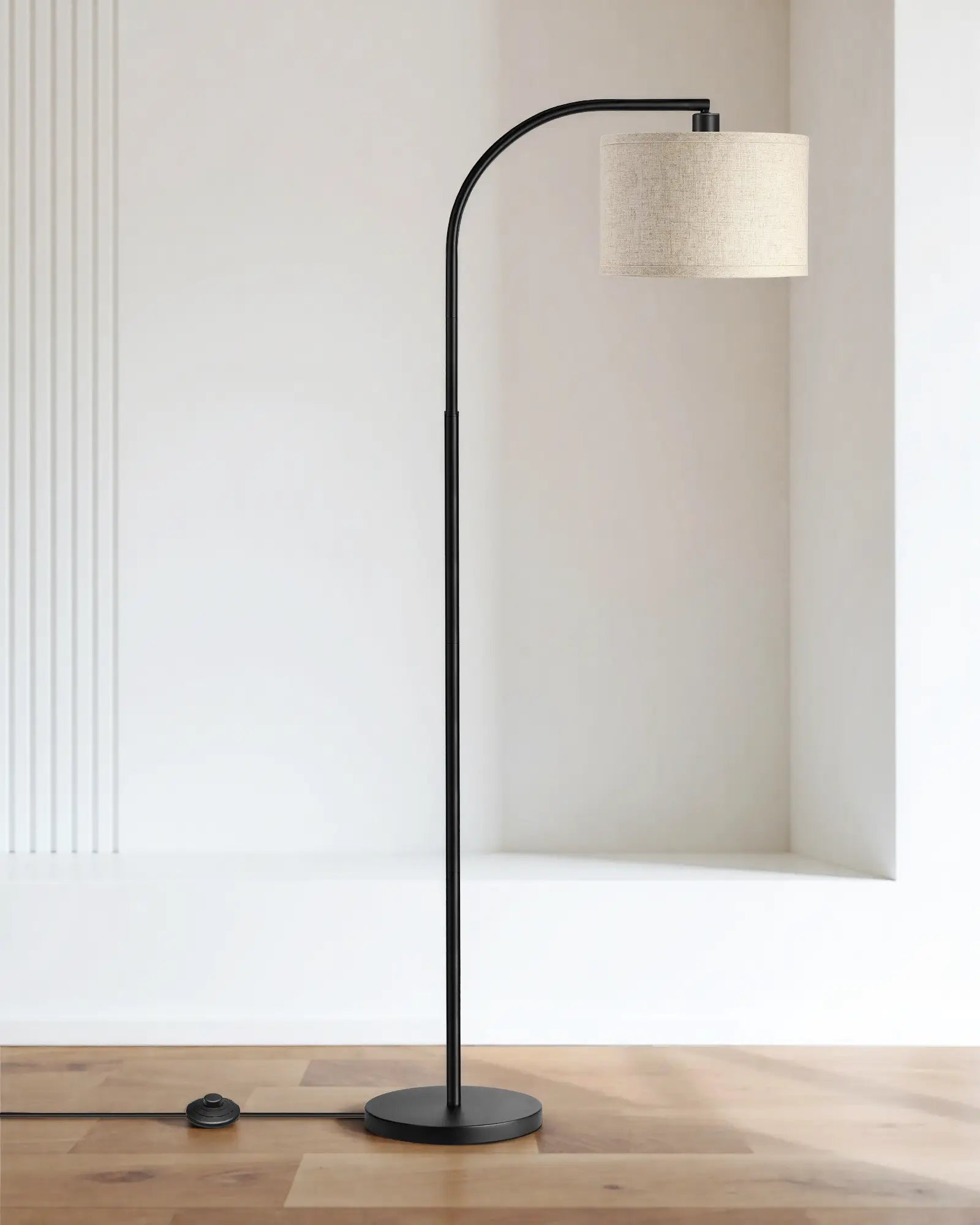 Modern Contemporary Arched Hanging Floor Lamp with a black curved arm and beige lampshade on a wooden floor.
