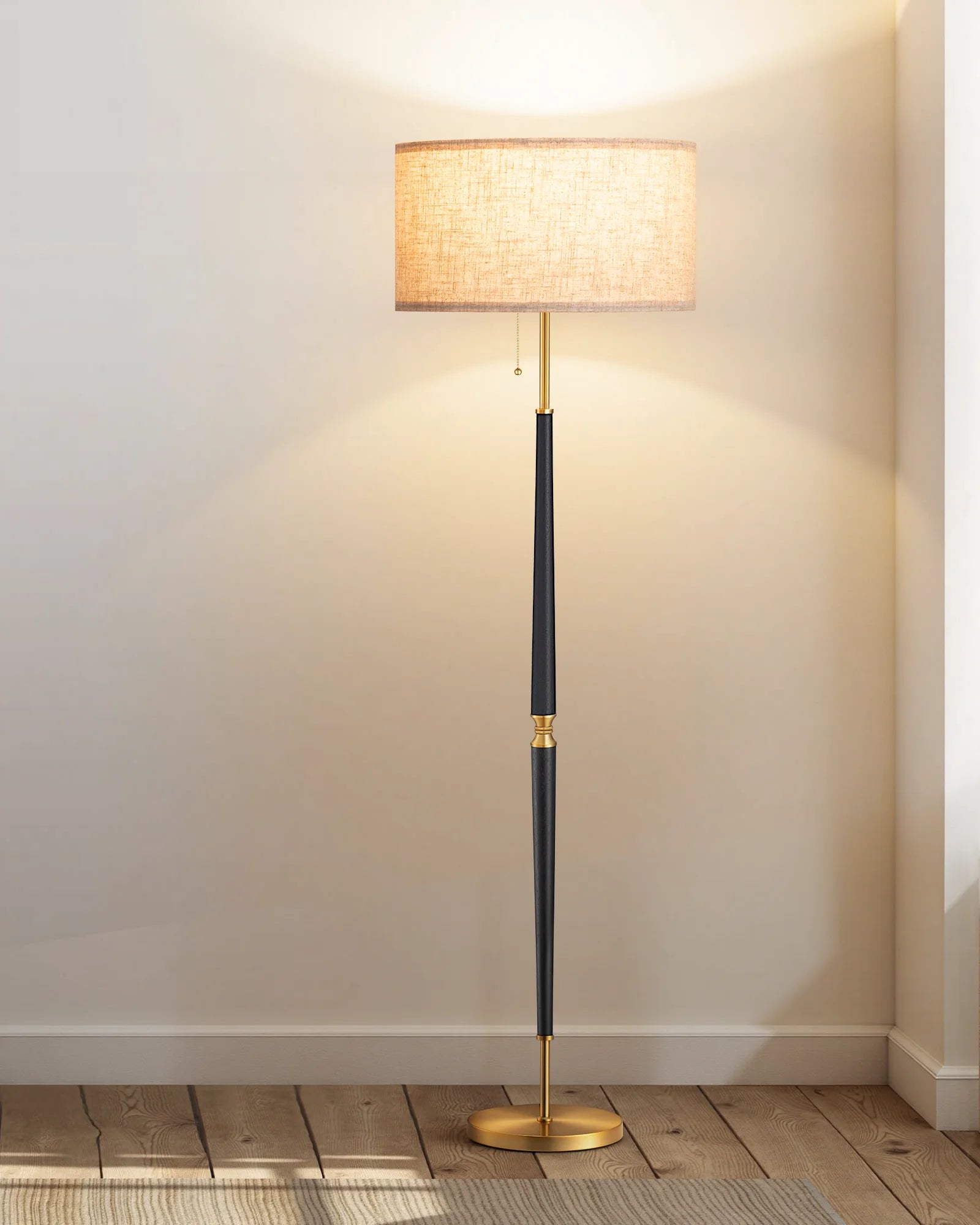 Floor lamp with a black and gold base and a beige lampshade on a wooden floor.