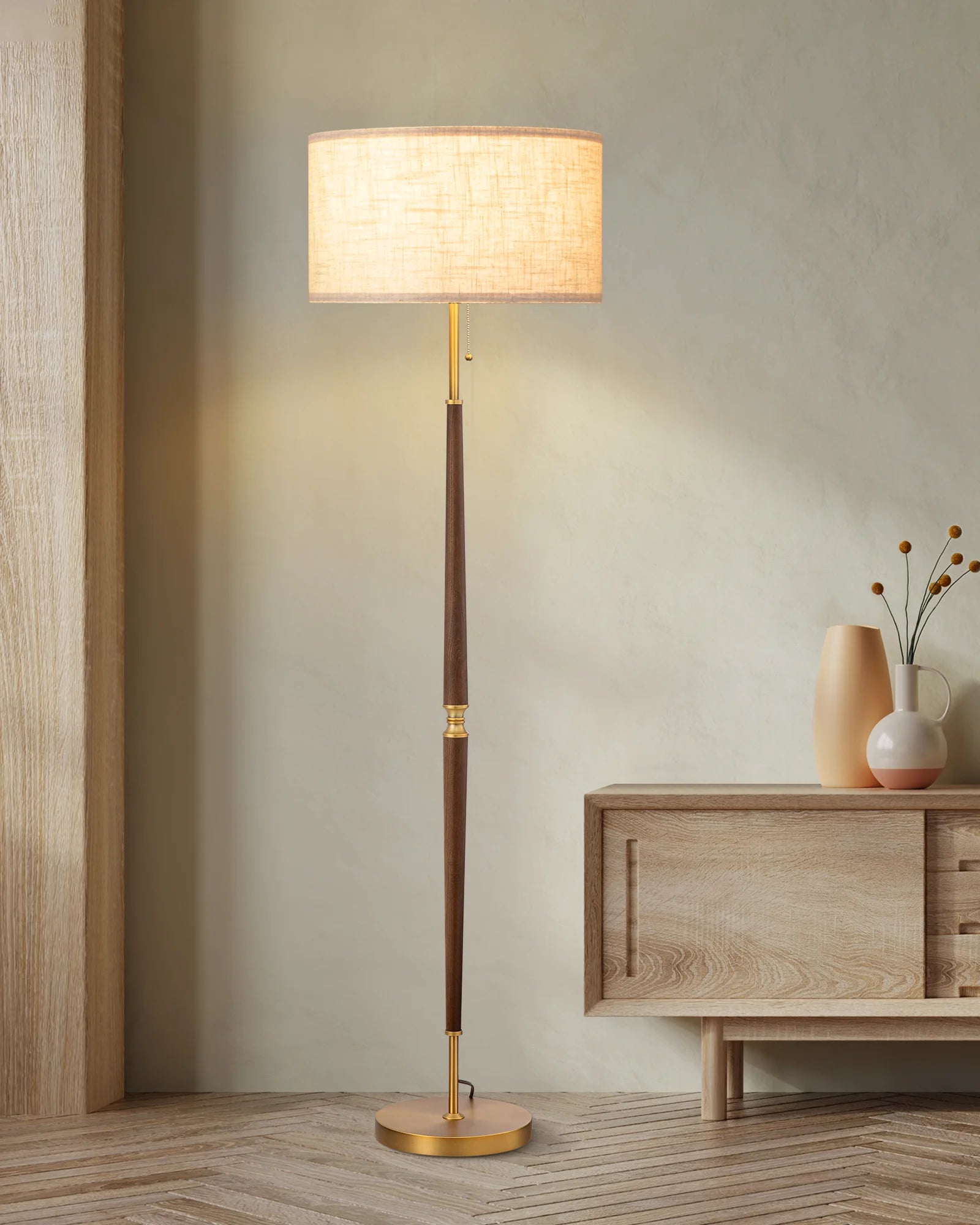 Floor lamp with a wooden base and beige shade in a room setting.