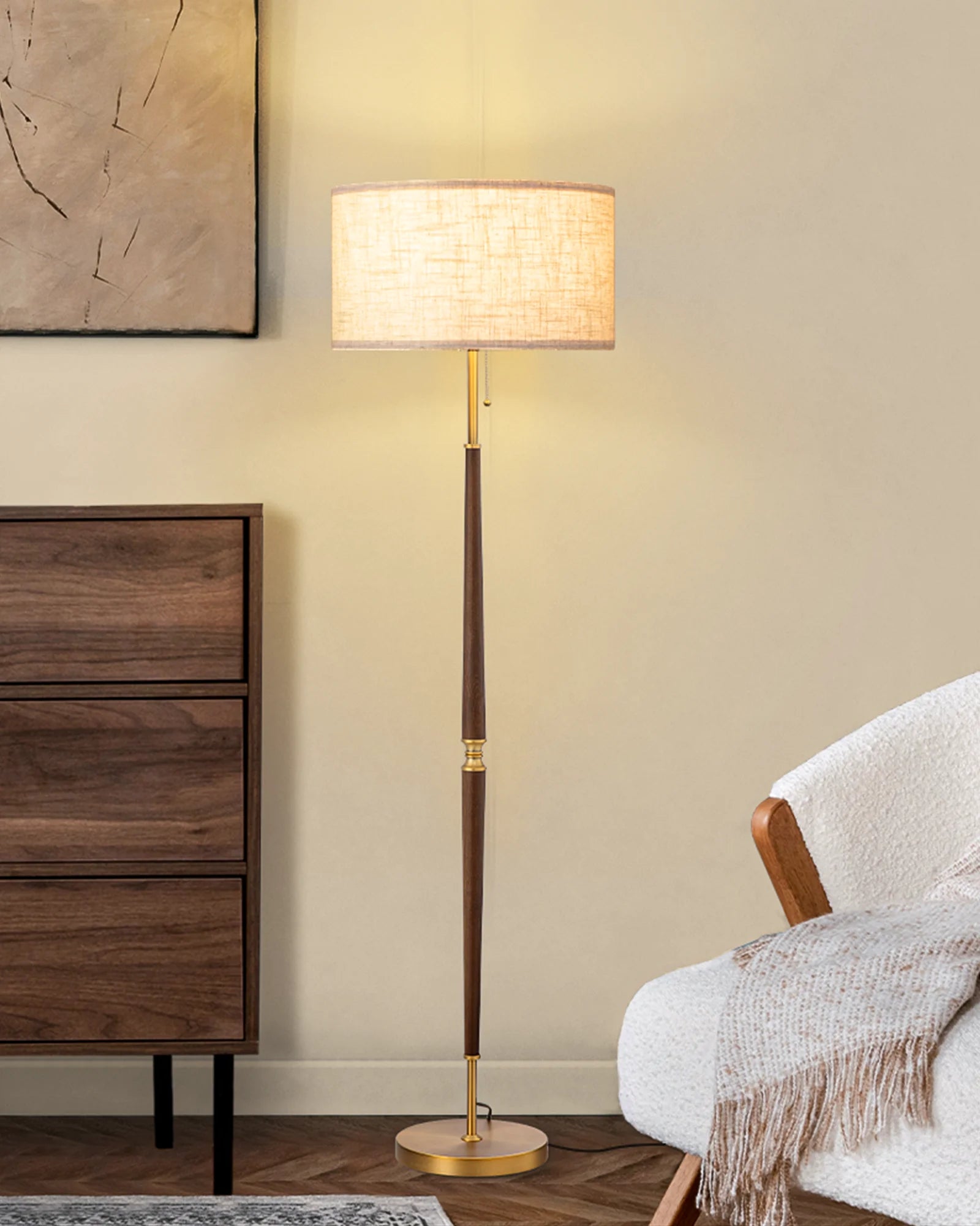 Floor lamp with a wooden base and gold accents in a room with a wooden dresser and chair.