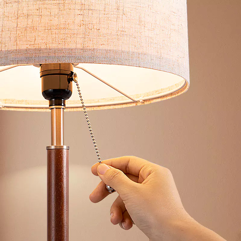 Hand adjusting a lampshade on a Classic Solid Wood Table Lamp with a beige background