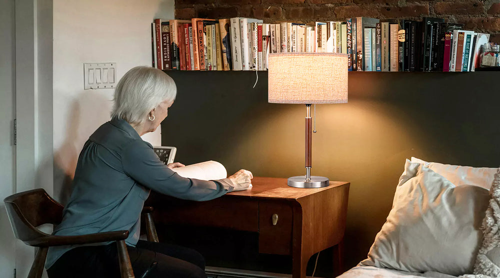 Person sitting at a desk with a Classic Solid Wood Table Lamp and books on a shelf in the background