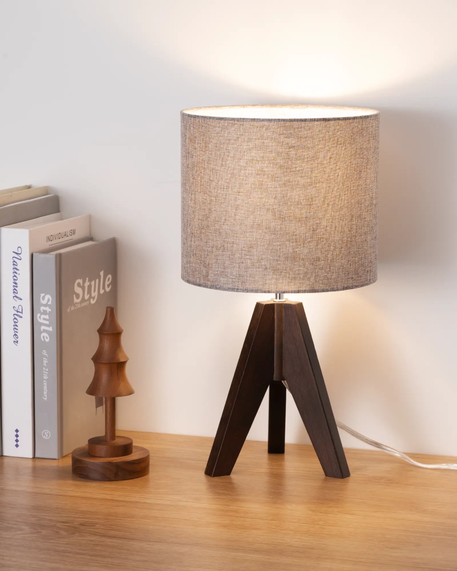 Table lamp with wooden base on a wooden surface next to books and a small decorative item.