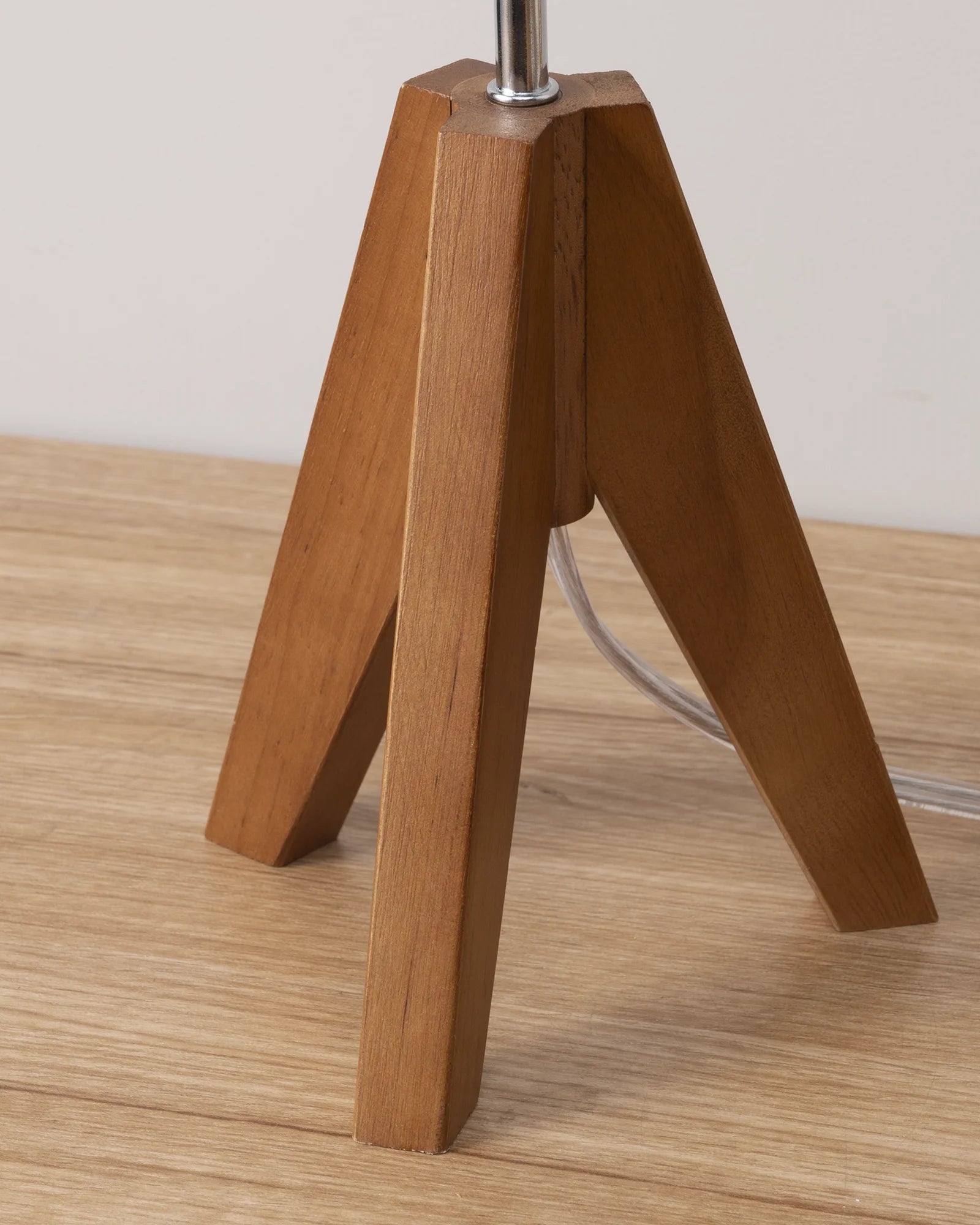 Mahogany brow wooden tripod lamp on a wooden surface with a neutral background