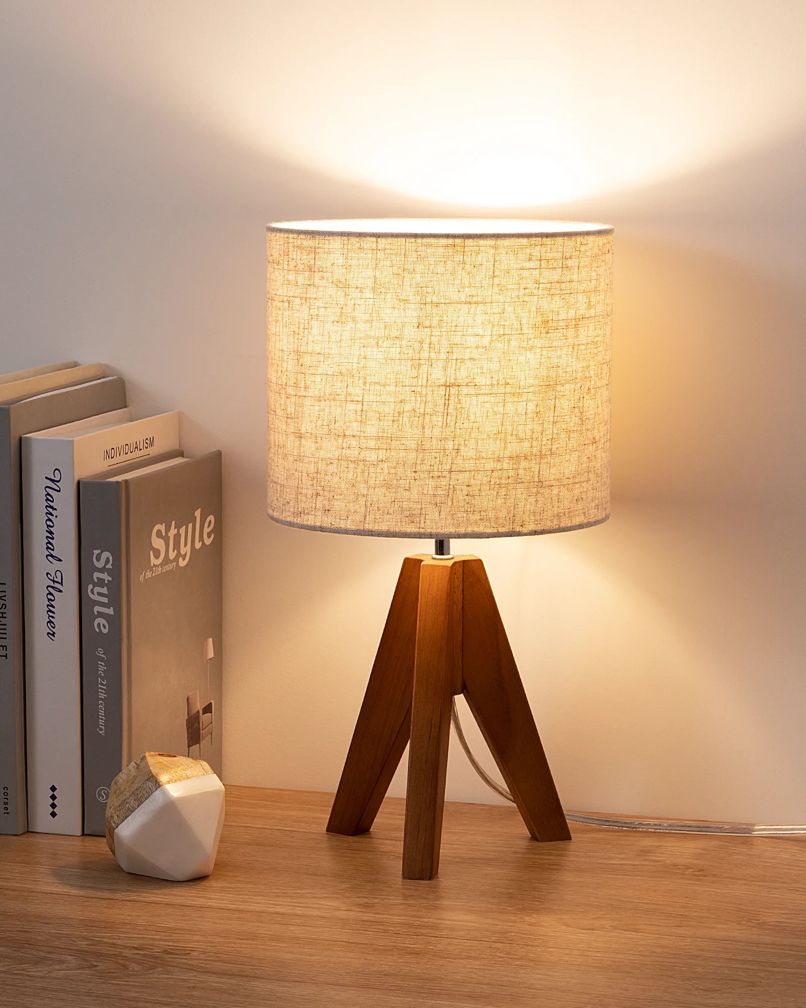 Small-Space Living Table lamp with mahogany brown wooden base and flax linen Lampshade on a wooden surface with books in the background.