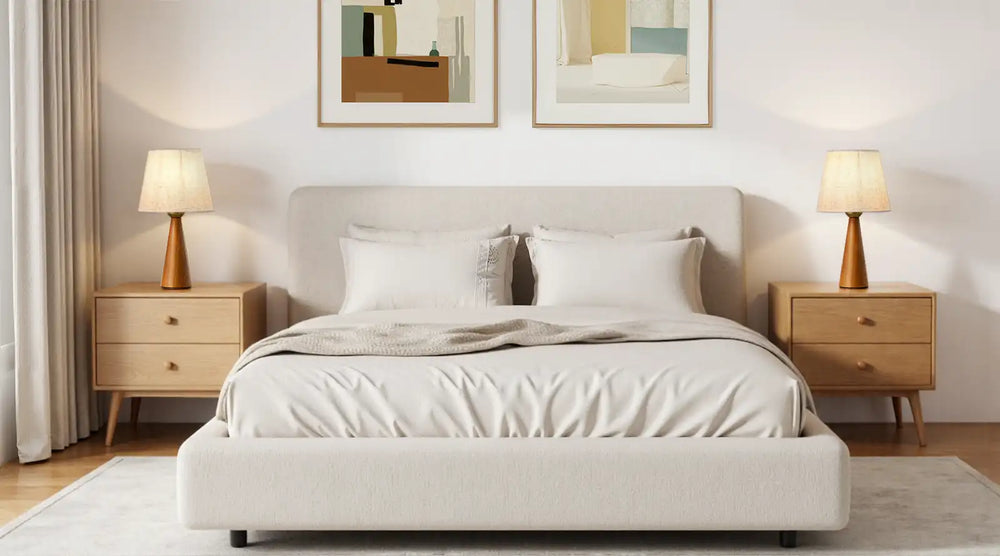 Neatly made bed in a bedroom with two lamps and framed pictures on the wall.