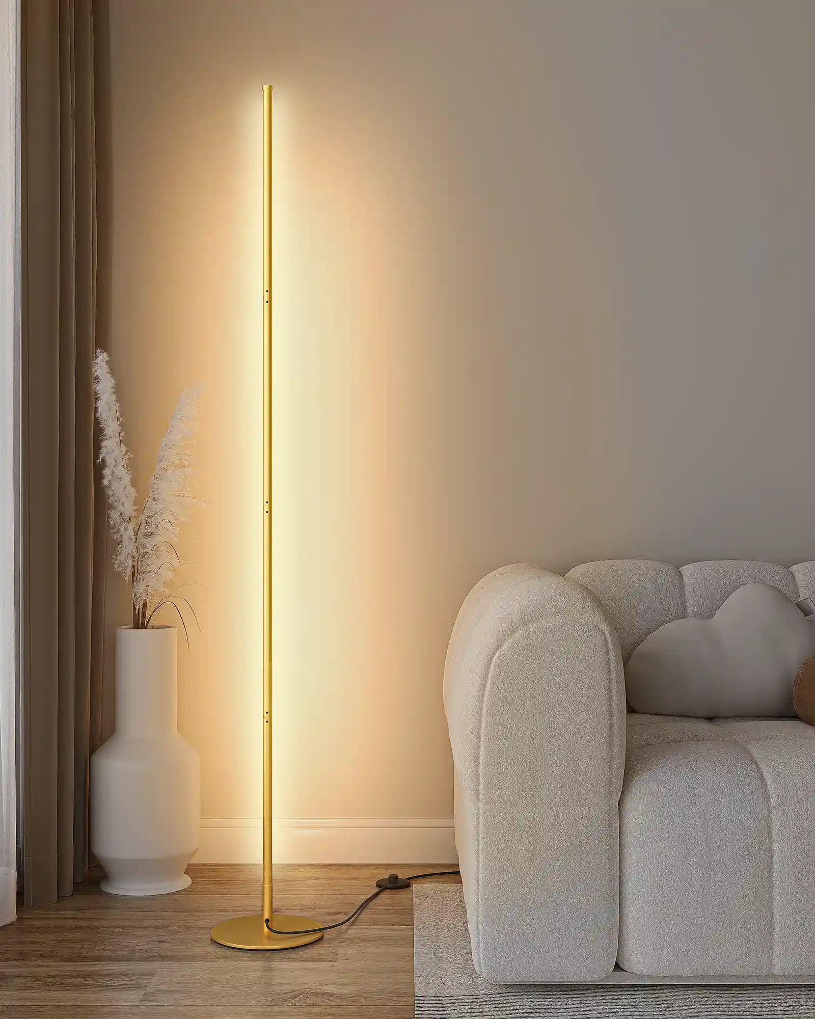 Gold floor lamp in a living room setting with a sofa and vase.