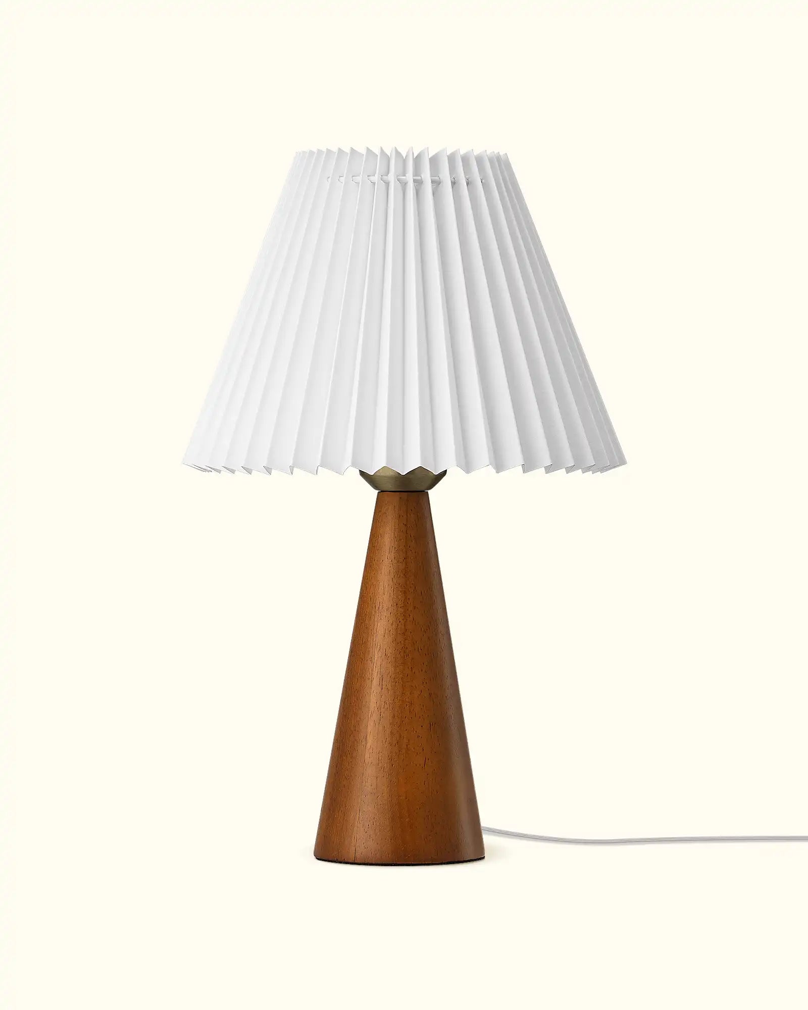 Table lamp with a wooden base and pleated white shade on a white background