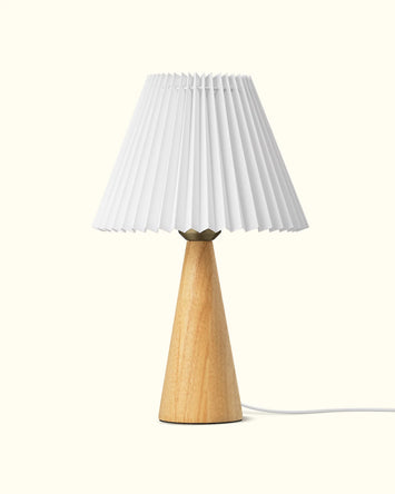 Table lamp with a wooden base and pleated white shade on a white background