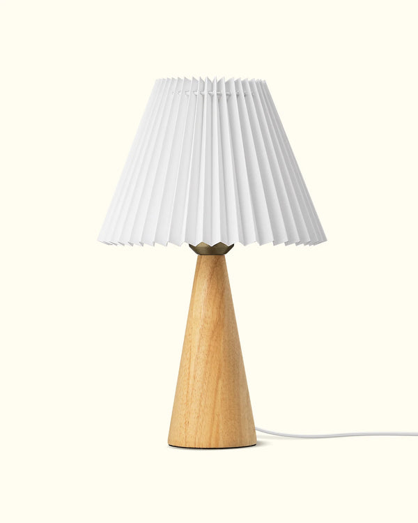 Table lamp with a wooden base and pleated white shade on a white background