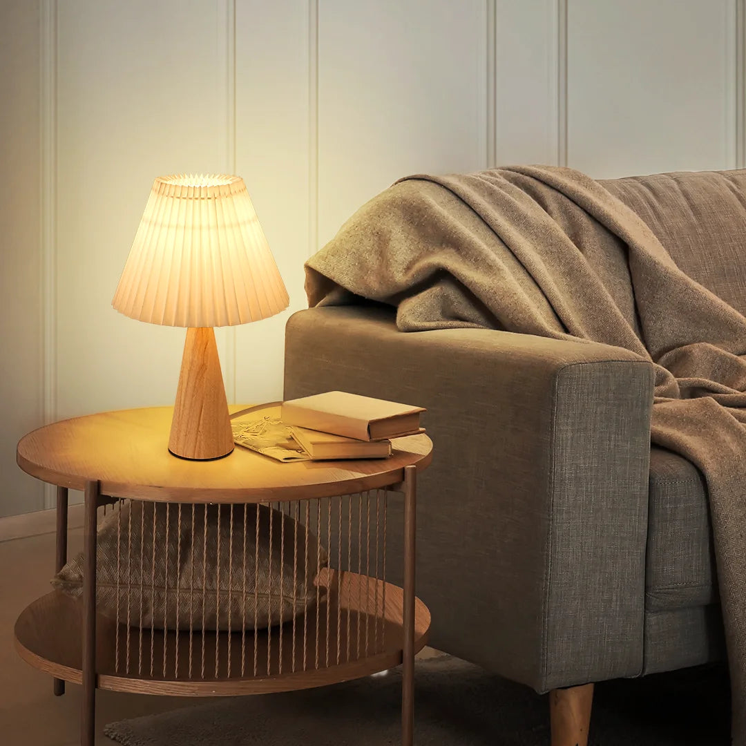 Cozy living room with a Pleated White Table Lamp on a side table and a blanket draped over a sofa.