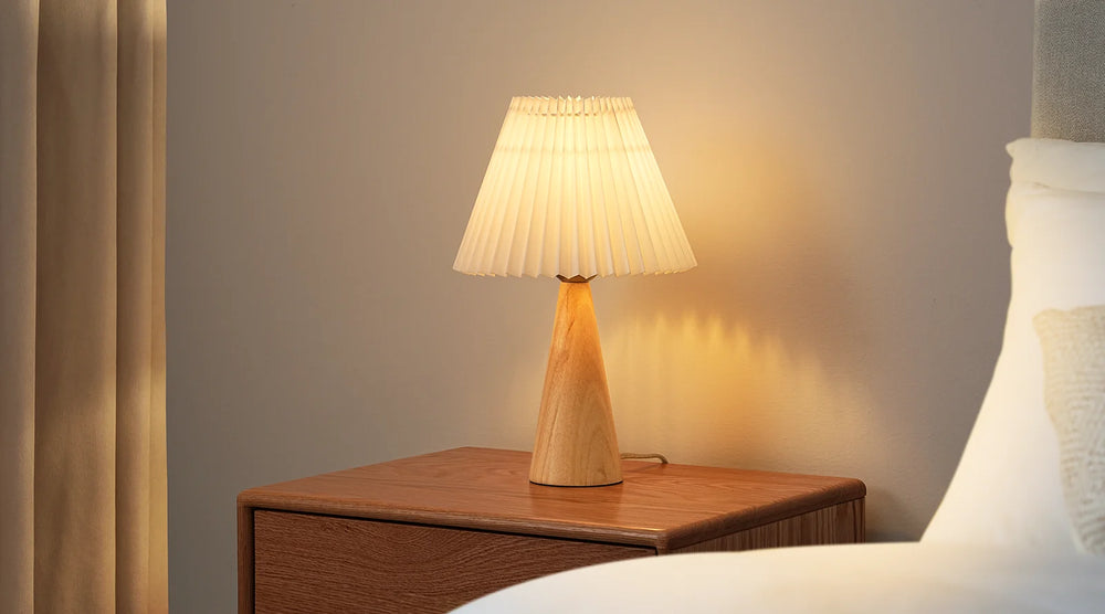 Pleated White Table Lamp on a wooden nightstand with soft lighting