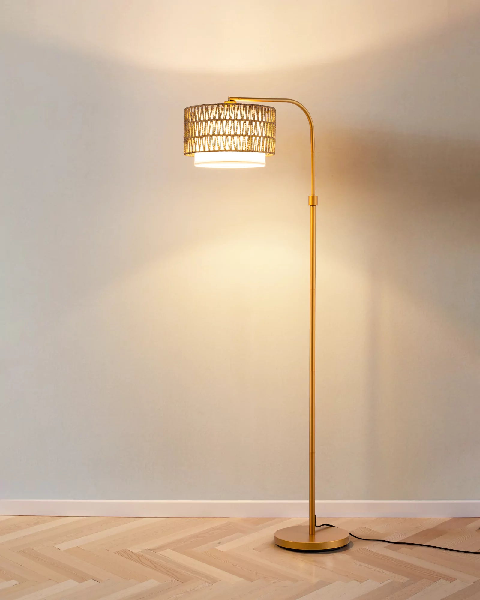  Rattan Arc Floor Lamp with wicker shade on a wooden floor against a white wall