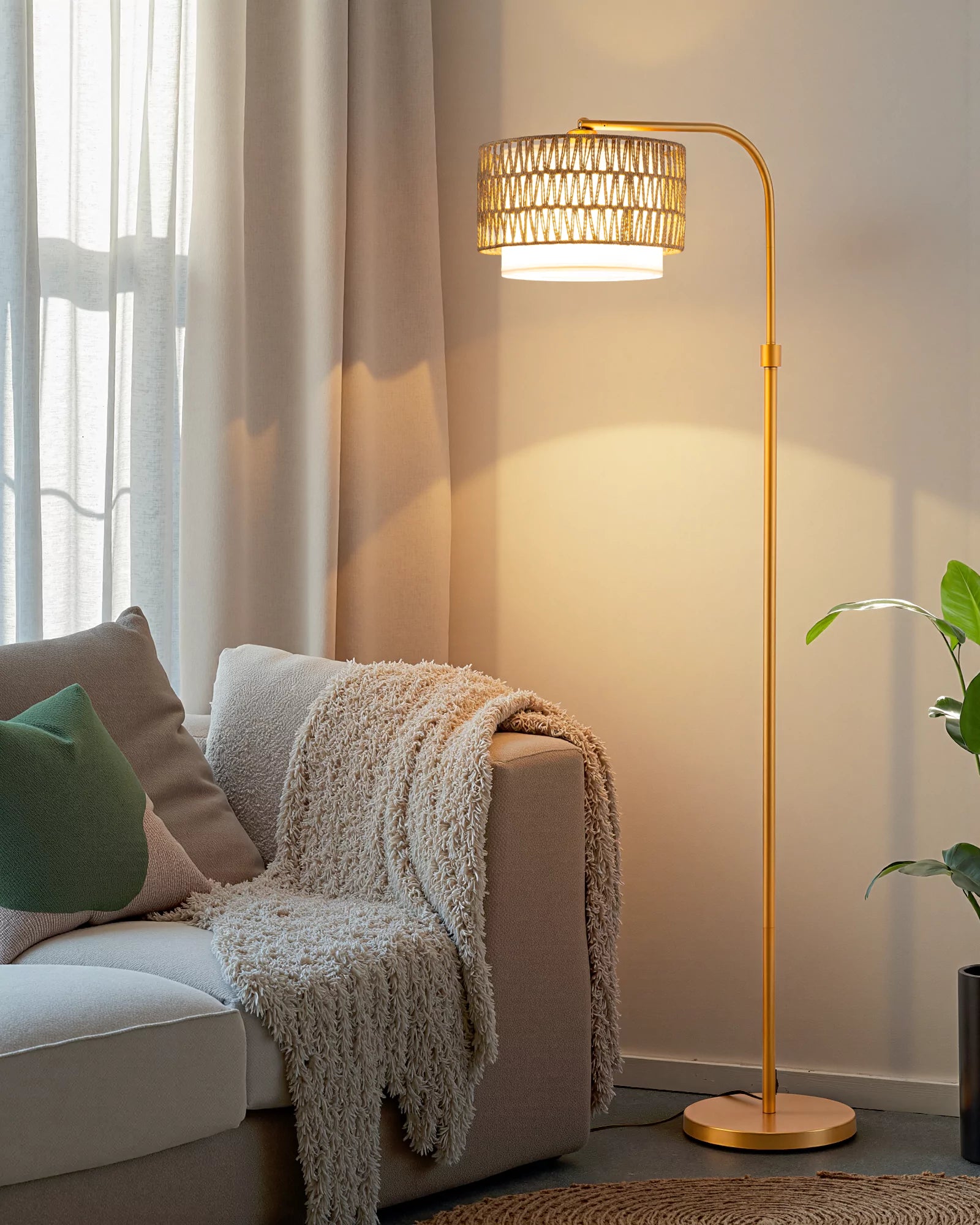 Gold Rattan Arc Floor Lamp in a living room setting with a couch and plant.