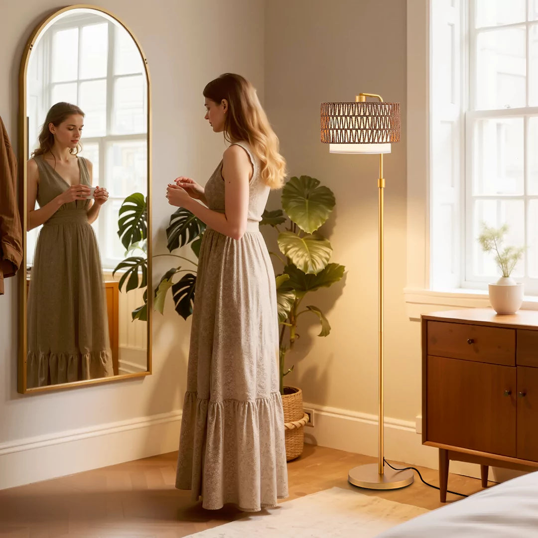 Woman in a long dress standing in a room with a mirror,  Rattan Arc Floor Lamp, and plants.