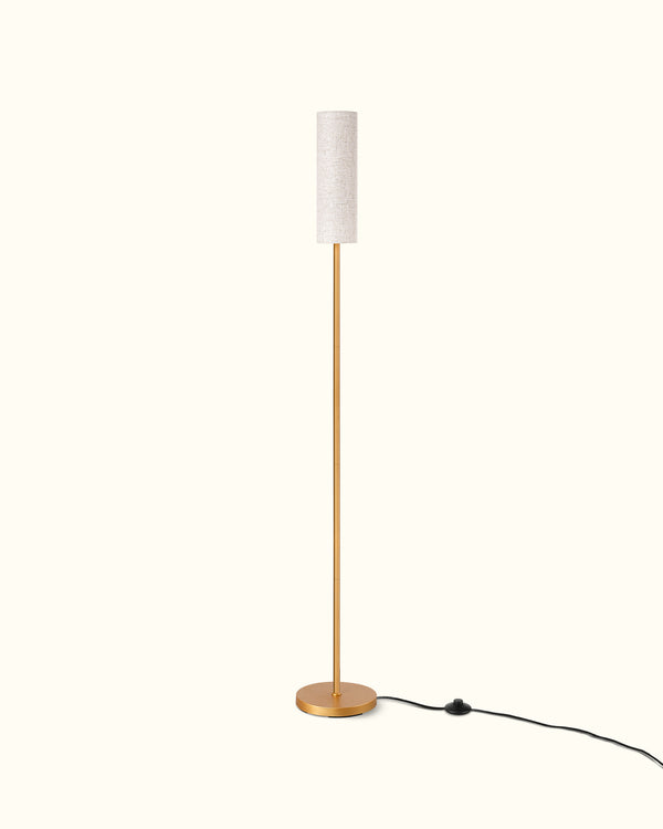 Floor lamp with a white shade and gold base on a white background