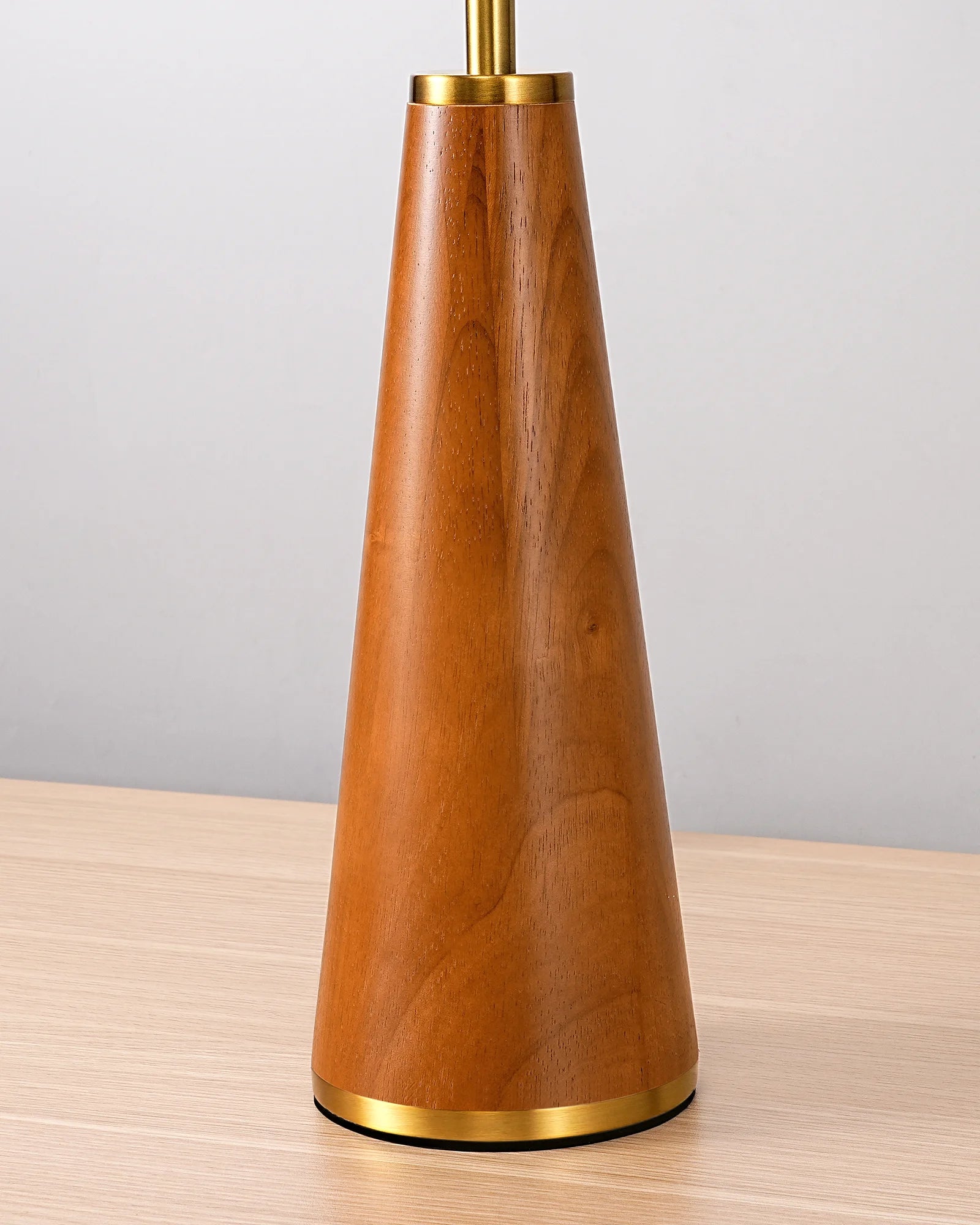 Wooden lamp with gold base and accents on a wooden surface