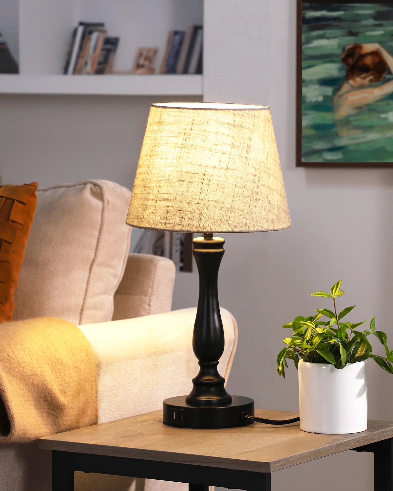Table lamp on a side table with a plant and sofa in the background