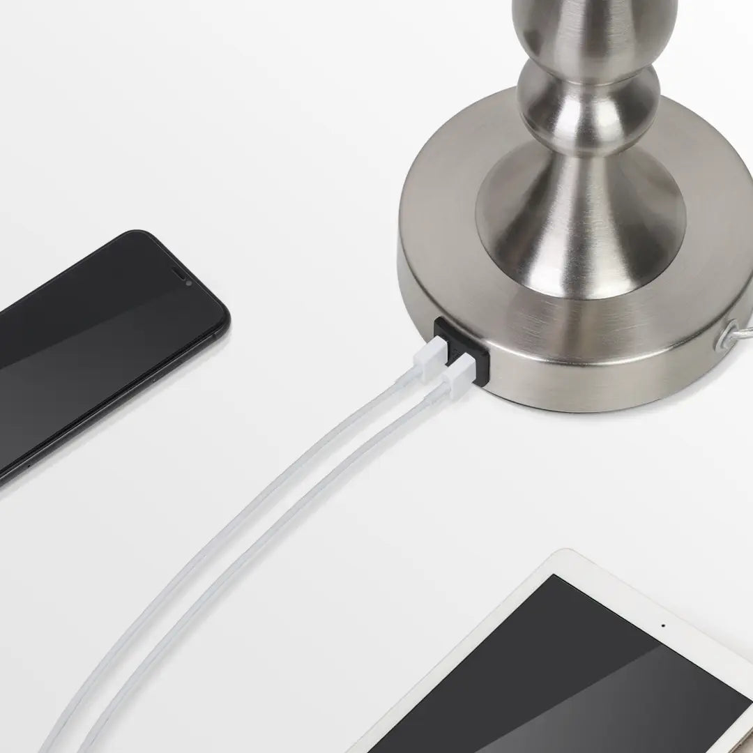 Silver lamp with USB cable connected to a smartphone and tablet on a white surface